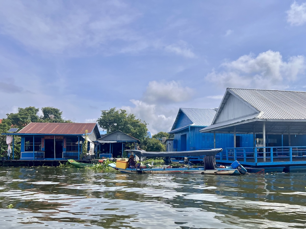 Colorful floating houses and a small wooden boat on Tonle Sap Lake, Cambodia, showcasing daily life in the vibrant floating village community.
